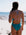 Woman in an Atlantic coloured JAYD one piece standing on a beach with ocean view. She is wearing the Airlie one piece