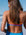 Woman in a Cancun blue fixed back one piece called Airlie standing on a beach