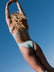 Woman in a  matcha green fixed back one piece against a clear blue sky. The style is the Lennox one piece