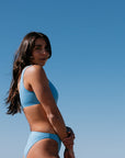Woman in JAYD Nalu blue bikini against a clear blue sky. Blue colour is called Breeze