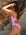 Woman in a fairy floss coloured one piece by JAYD, standing against a rocky background.