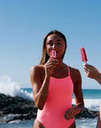 Woman in a vibe coloured JAYD one piece holding a popsicle by the ocean