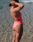 Person wearing a bright coloured Vibe JAYD one piece standing in shallow water. One piece is the Tallow style.