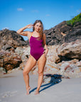 JAYD Swimwear model standing on a beach on a sunny day in the Airlie one piece contrasting swimsuit in sangria and flare colourways.