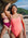 Surf life saving athlete Sara standing on a rocky beach wearing the JAYD Swimwear Airlie one piece in vibe with lilac haze shoulder straps.