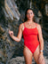 Ski paddler Jenaya Massie leaning against a rock at the beach wearing the JAYD Swimwear Airlie one piece swimsuit.