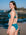 JAYD model Milly wearing the Amalfi bikini bottoms in Cove on a rocky beach with ocean waves and a clear blue sky in the background.