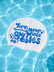 A white swim cap floating on rippling blue pool water, printed with the phrase 'Turn your troubles into bubbles' in blue bubble lettering.