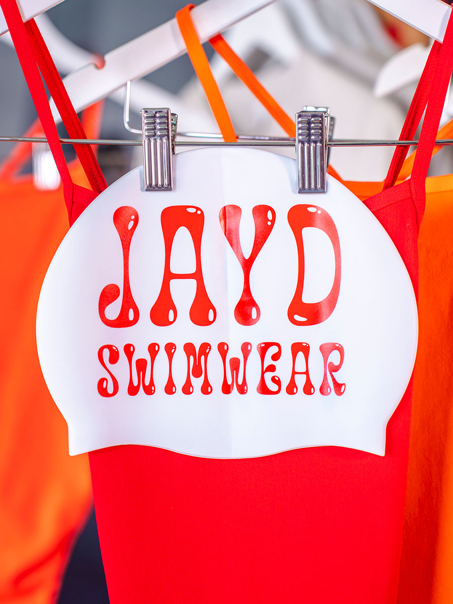 White swim cap with red JAYD swimwear text.