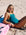 JAYD Swimwear athlete Brodee Trinca wearing the Cove Finley one-piece swimsuit with Moss green shoulder straps reclines on a pink ski on a sandy beach.