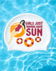 A white swim cap with a colorful graphic of a woman on an orange float and the text 'GIRLS JUST WANNA HAVE SUN' is shown floating on blue pool water.