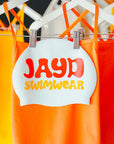 Orange swimwear with a 'JAYD Swimwear' label on a hanger.