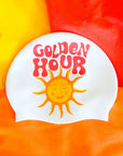 White swim cap with 'Golden Hour' text and sun illustration on a colorful background