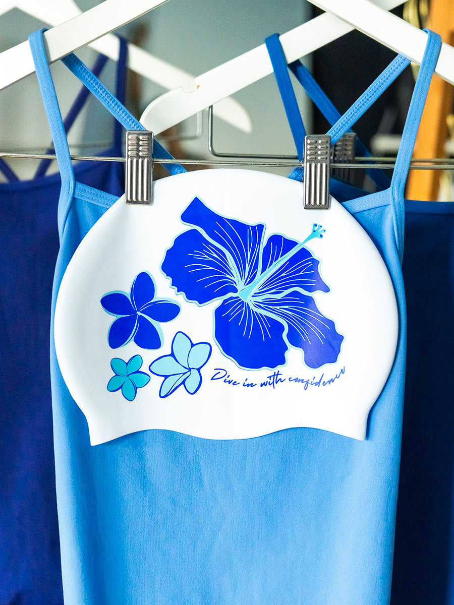 Four tropical blue flowers illustrated on a white swim cap with the JAYD Swimwear 'dive in with confidence' signature phrase.