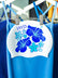 White swim cap hanging on a rack with blue hibiscus flowers, matching JAYD Swimwear's blue swimsuit range.