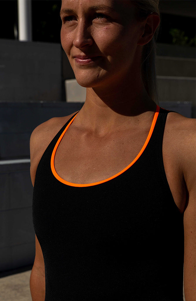 Close-up view of the Breeza one piece by JAYD swimwear. Colour featured is Black with contrasting Neon Orange strap detailing 