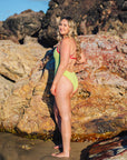 Woman wearing JAYD Swimwear Zambia one piece swimsuit in Kiwi green with contrasting Tart straps. Suit designed to raise awareness for Cure Cancer.