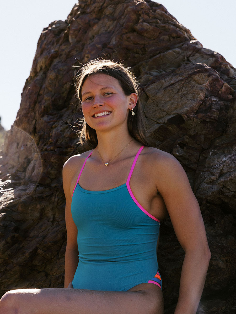Athlete Kate wears the fixed back Zambia one piece in the colour Atlantic, the suit has contrasting pink sorbet straps and mid coverage.