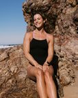 Athlete Claudia wears the Zambia one piece in the colour black with contrasting lilac haze straps, this piece is built for performance.
