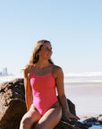 Athlete Molly wearing the Lennox one piece designed by JAYD Swimwear in the colour Pink Sorbet. this fixed back one piece is perfect for catching waves at the beach.