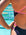 Close-up of Ella Ramsay wearing a dark acai purple JAYD Swimwear Lennox one-piece swimsuit with bright pink fairy floss and multicolor striped side straps, standing by a swimming pool.