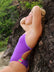 Female swimmer wearing a JAYD Swimwear athletic Lennox one piece swimsuit in Murasaki purple, leaning against a rock.