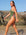 Australian triathlete, Charlotte Derbyshire, in a Olive green JAYD Swimwear athletic Lennox one piece swimsuit, standing on a rocky beach with clear blue sky.