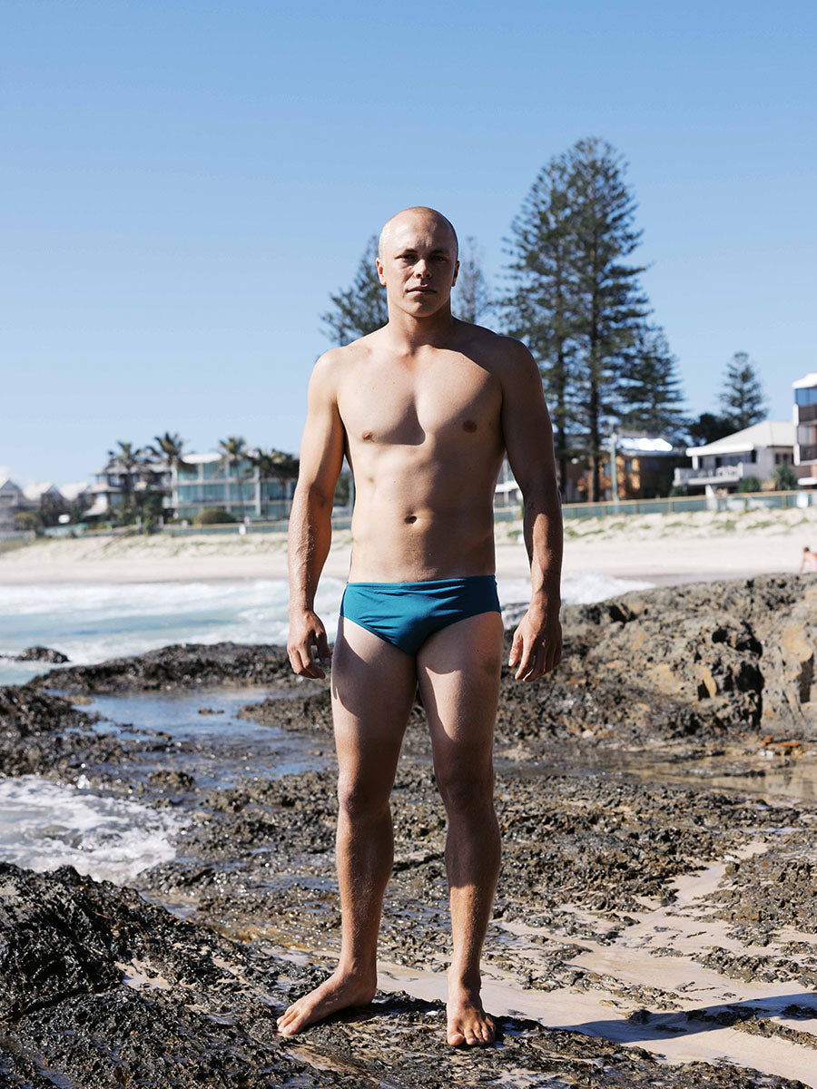 Front view of ocean athlete Tanner wearing the Ramshark men’s swim bottom in Cove by JAYD Swimwear. A chlorine-resistant design made for endurance, comfort, and confident movement in the water.