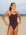 Front view of an athletic woman wearing a dark brown athletic JAYD Swimwear Riva one piece swimsuit in cacao, standing on a beach.