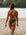 Back view of a female athlete wearing a JAYD Swimwear athletic one piece swimsuit, Riva in Olive green, walking on a beach.