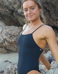 JAYD Swimwear, athletic one piece called Tallow in the colour black, lifestyle image at the beach.