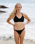 Emma Woods wearing the black Tazzie Top by JAYD Swimwear, showing the supportive front design of the chlorine-resistant performance swim top made for surf athletes and training.