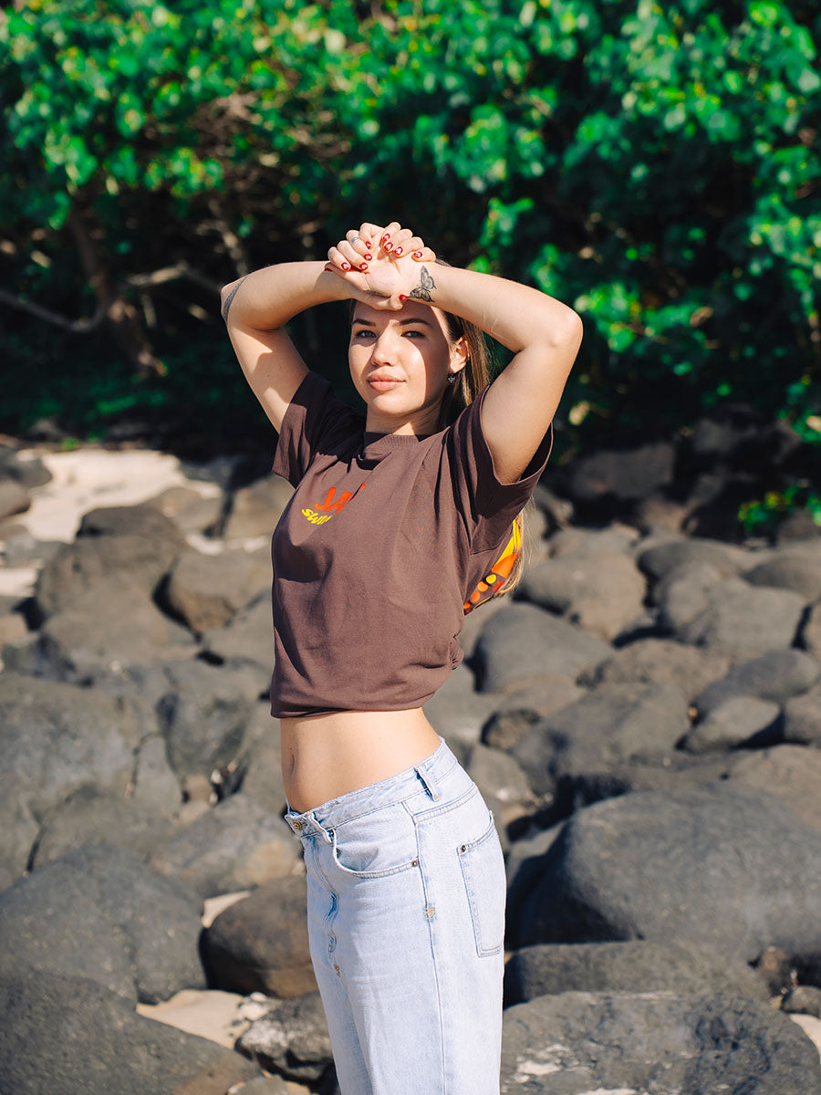 Brown oversized JAYD Swimwear t-shirt with a retro orange and yellow logo print on the front, a boxy fit tee for everyday beach style.