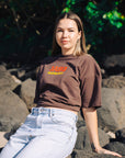 Front detail of JAYD Swimwear's brown oversized tee, printed with a retro-style orange JAYD and yellow Swimwear logo.