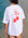 Back view of a model in JAYD Swimwear's white oversized tee, printed with a red disco-ball cherry graphic and Mon Cheri text.