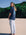Woman wearing a navy JAYD Swimwear oversized boxy tee with a light blue tropical graphic print on the back, paired with light wash denim jeans on the beach.
