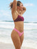 Female swimmer in a JAYD Swimwear Torquay bikini top in Sangria and pink bikini bottoms, standing on a beach.