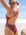 Surf Ironwoman, Brodee Trinca, standing on a beach wearing JAYD Swimwear athletic one piece swimsuit, Apsley in Sangria.