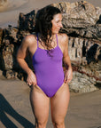 Madi wears the Riva one piece by JAYD Swimwear in the colour Murasaki. This piece is built for performance and is a tie-back.