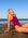 Side view of model sitting on a rock wearing JAYD Swimwear athletic one piece Finley in Sangria.