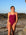 Front view of model on a rock wearing JAYD Swimwear full coverage Tallow one piece in Sangria.