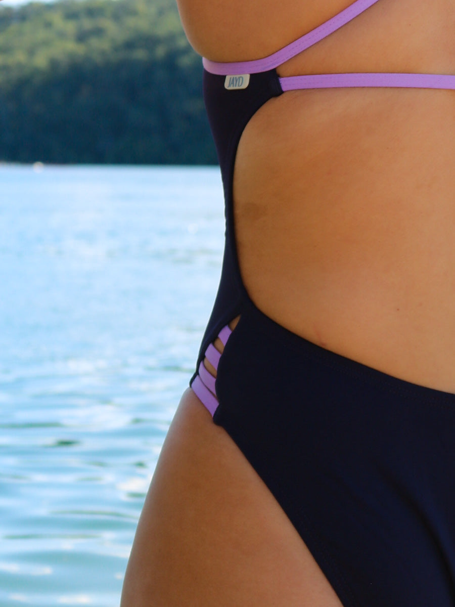 Close hip view of model on beach wearing JAYD Swimwear athletic one piece swimsuit Zambia in Acai.