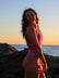 Side view of model on a beach at sunrise wearing JAYD Swimwear athletic one piece swimsuit Zambia in Orchid Pink.