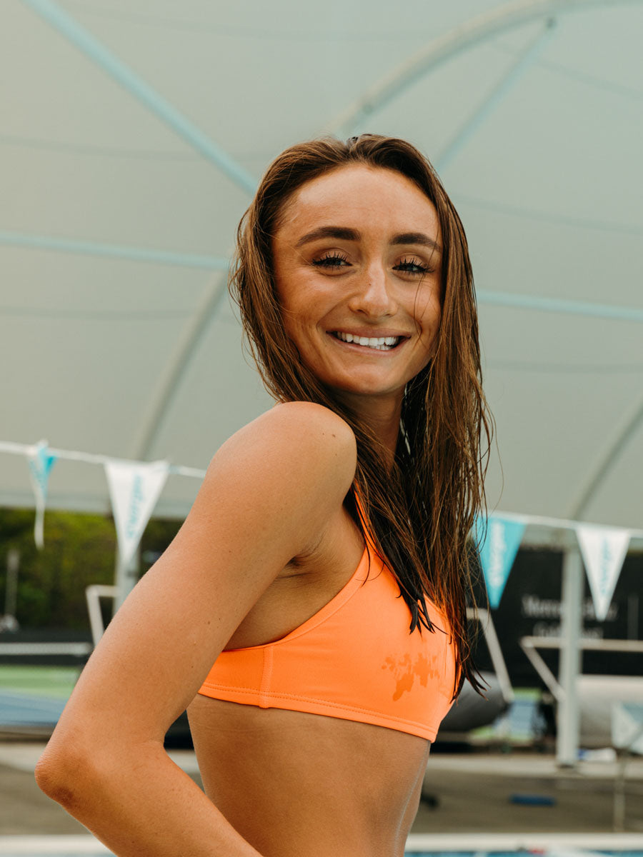 Side view of athletic fixed-back Torquay bikini top in Neon Orange by JAYD Swimwear.