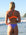 Back view of model on a beach wearing JAYD Swimwear athletic bikini top Torquay in Neon Orange.