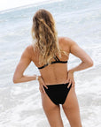 Back view of the JAYD Swimwear ZALI bikini bottom in Black on Emma Woods, featuring flattering mid bum coverage and a supportive waistband.