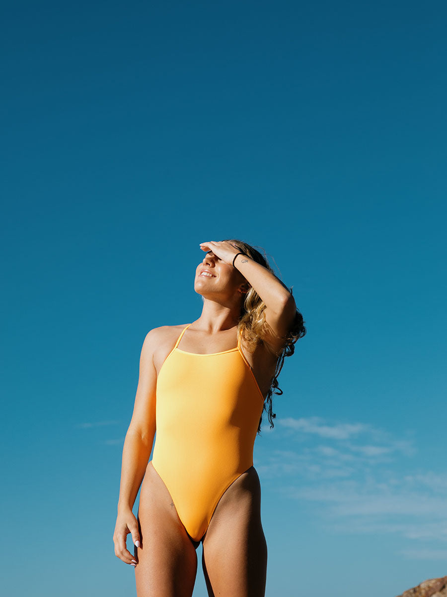 Athletic woman wearing JAYD Swimwear Albi One Piece in Sunshine with high leg cut, supportive design, and chlorine-resistant fabric