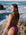 Woman in a fairy floss pink fixed back one piece standing on a rocky beach with ocean waves.