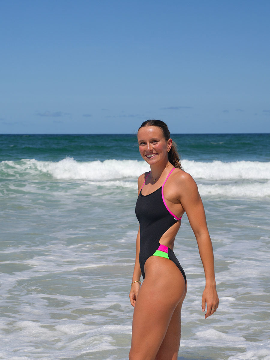 Engineered for athletes, worn by champions. Molly makes waves in the Ibiza One Piece swimsuit in Black with bold contrasting Pink Sorbet hip cut-outs.