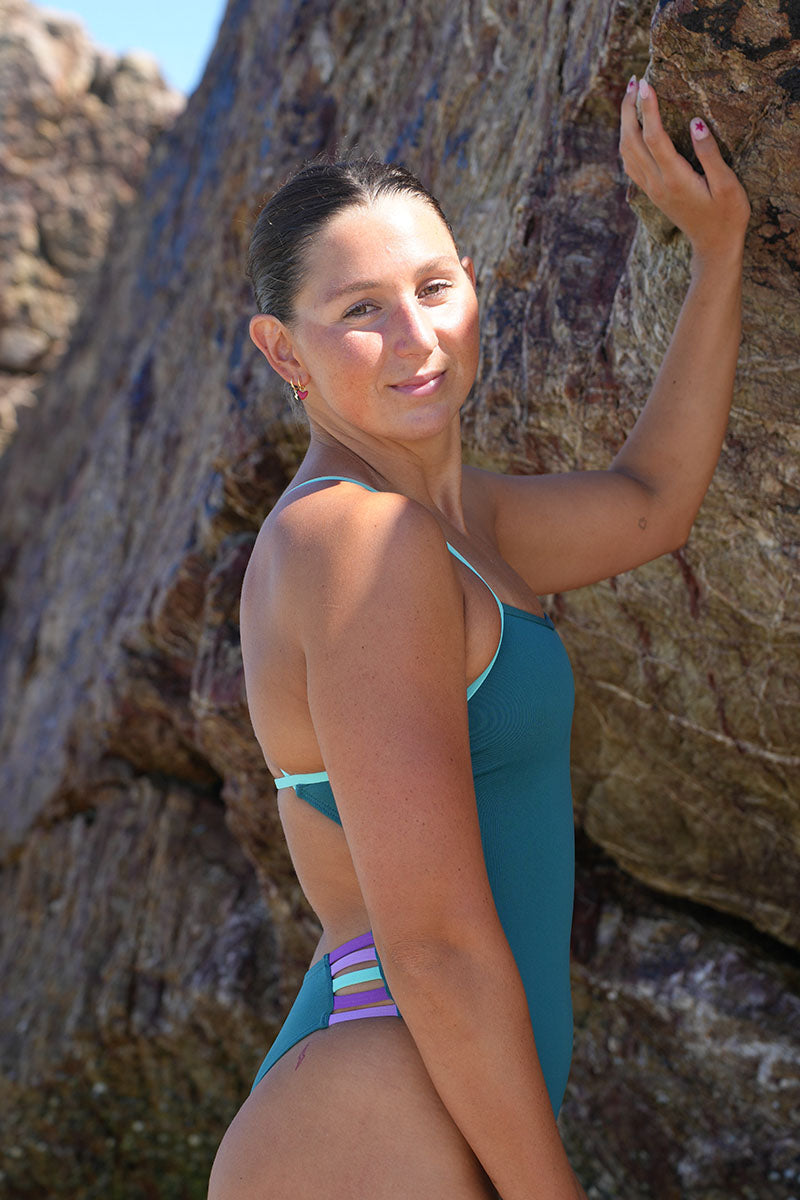 Athlete Madi Armstrong wearing the JAYD Swimwear Lennox One Piece in Cove × Seamist — side profile view highlighting the bold contrast hip cut-out details.